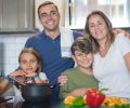 A joyful family of four cooking together in a modern kitchen, highlighting family bonding and culinary activities.