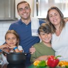 A joyful family of four cooking together in a modern kitchen, highlighting family bonding and culinary activities.