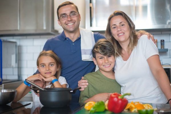 A joyful family of four cooking together in a modern kitchen, highlighting family bonding and culinary activities.