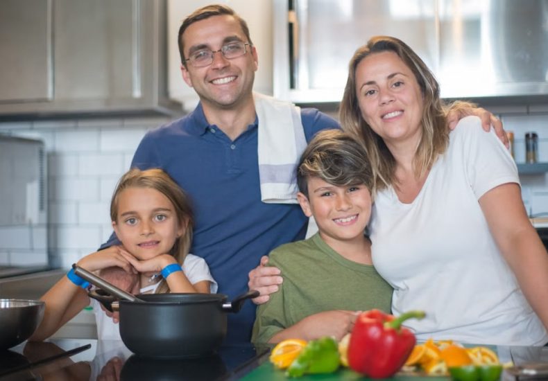 A joyful family of four cooking together in a modern kitchen, highlighting family bonding and culinary activities.