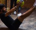 Focused man performing core exercises with a medicine ball in an indoor gym highlighting fitness and strength.