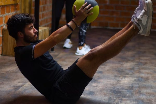 Focused man performing core exercises with a medicine ball in an indoor gym highlighting fitness and strength.